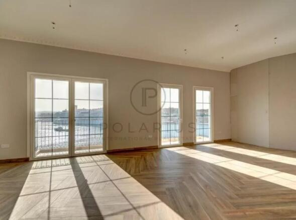 Sunlit empty room with large windows and parquet f