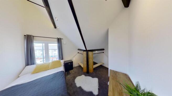 Bright bedroom with vaulted ceiling and beams...