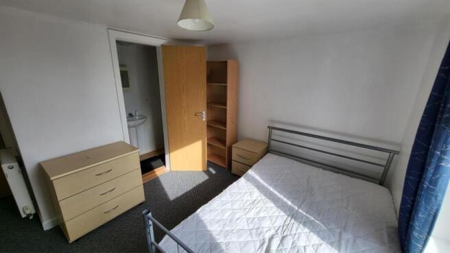 Bright, simply furnished bedroom with a double ...