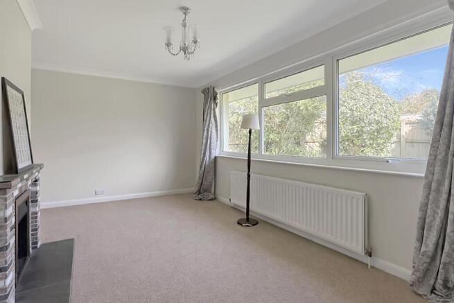 Spacious living room with fireplace and radiator.j
