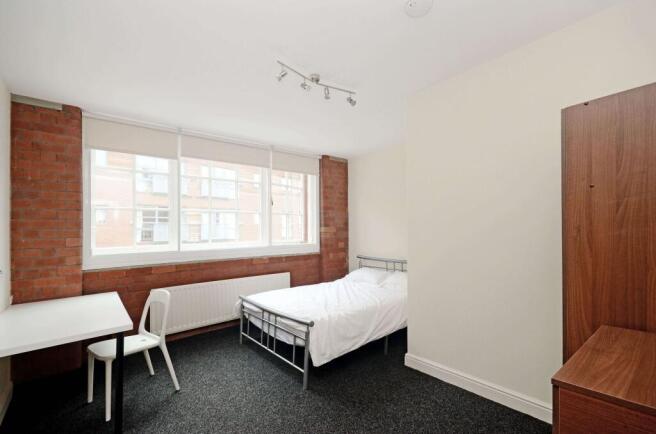 Bright, modern bedroom with exposed brick accen...