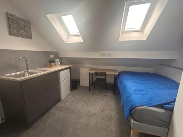 Bright attic room with kitchenette and bed...