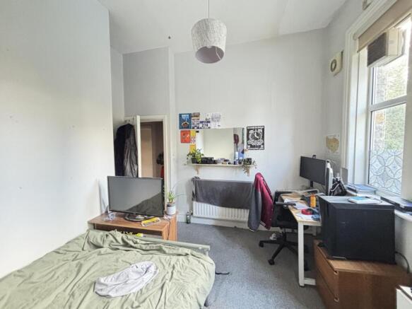 A cozy bedroom featuring a bed, desk, and windo...