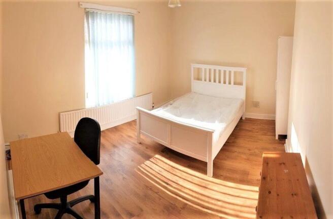 Bright, simply furnished bedroom with wooden fl...