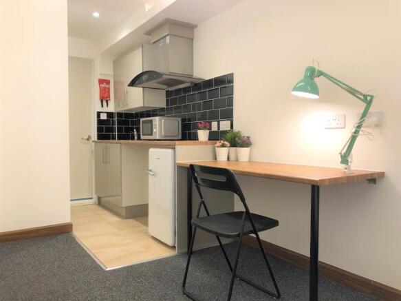 A compact, modern kitchen area featuring a slee...