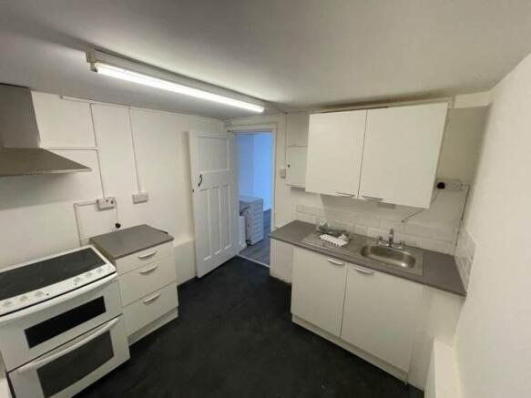 Compact fitted kitchen with modern white units...