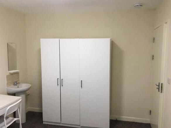 A neat and simple single bedroom featuring a wh...