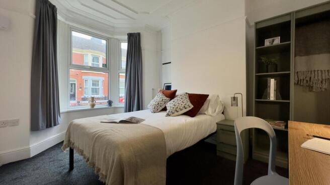 A bright and inviting double bedroom with styli...