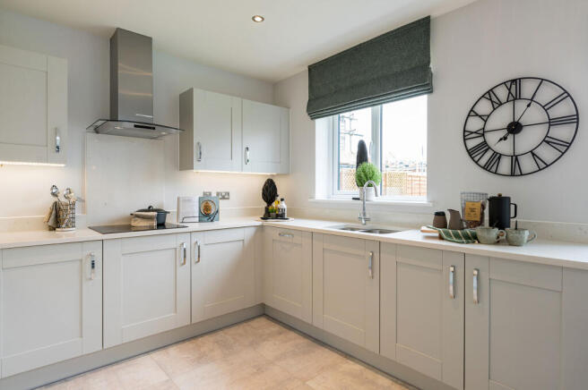 A modern, light-colored kitchen with a stainless steel range hood and cabinets in the foreground