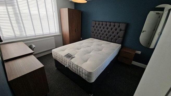 Bright, neatly furnished bedroom with a comfort...