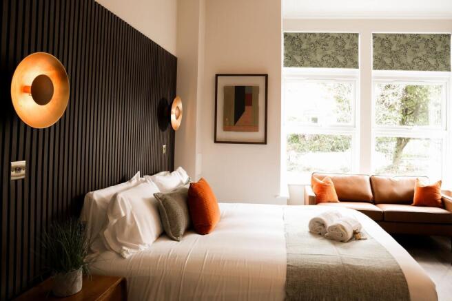 Bright modern bedroom with comfy bed and sofa...
