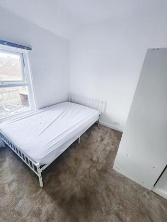 Bright, freshly painted bedroom with a white me...