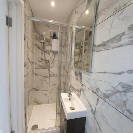 Modern tiled bathroom with a glass-enclosed sho...