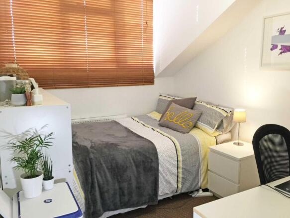 Cozy, neatly made bedroom with soft grey and ye...