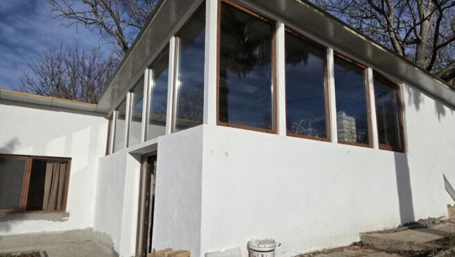 Corner of the house showing large glass windows and white painted walls