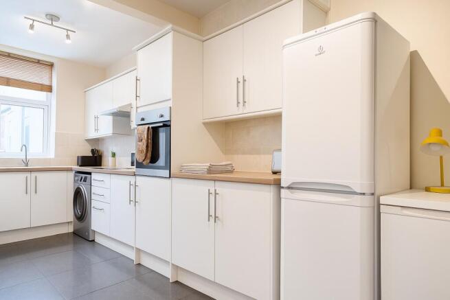 Bright, modern kitchen with white cabinetry, in...