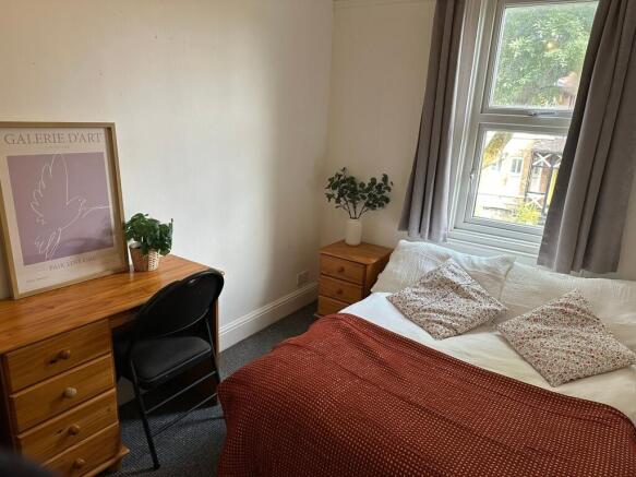 A cozy bedroom featuring a neatly made bed with...