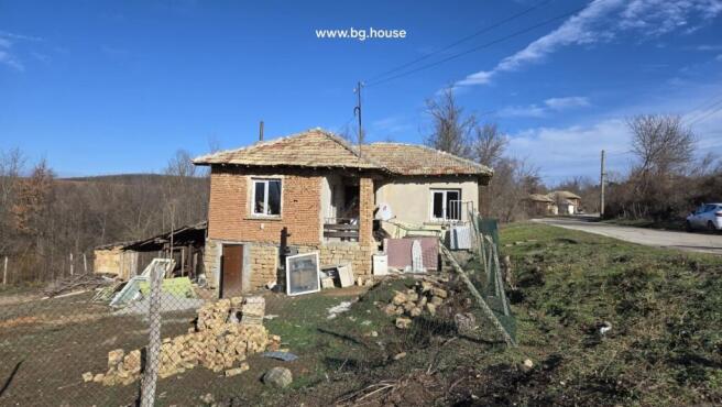 Exterior view of a traditional Bulgarian house showing stone lower walls and brick upper walls with a tiled roof