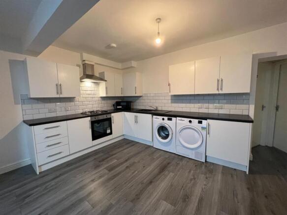Modern open-plan kitchen with white cabinetry, ...
