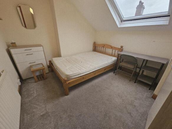 Bright attic double bedroom with a wooden bed f...