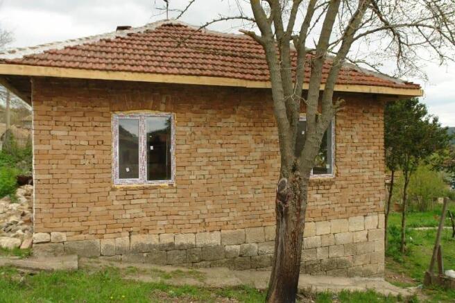 Side perspective of the rural house showing exposed brick walls and two newly installed windows.