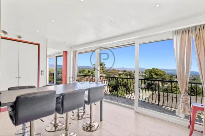A modern dining area with bar stools features larg