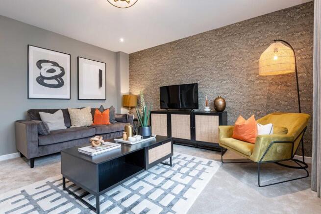 A modern living room features a dark grey sofa with orange accent pillows in the foreground