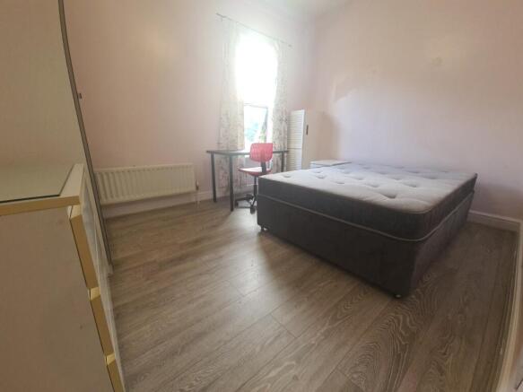 A spacious double bedroom with a comfortable be...
