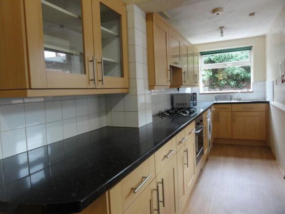 Bright galley kitchen with a long black granite...