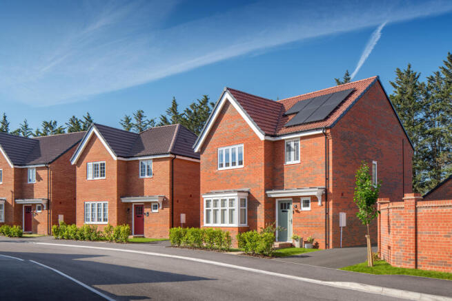 A paved road leads past modern brick houses with solar panels