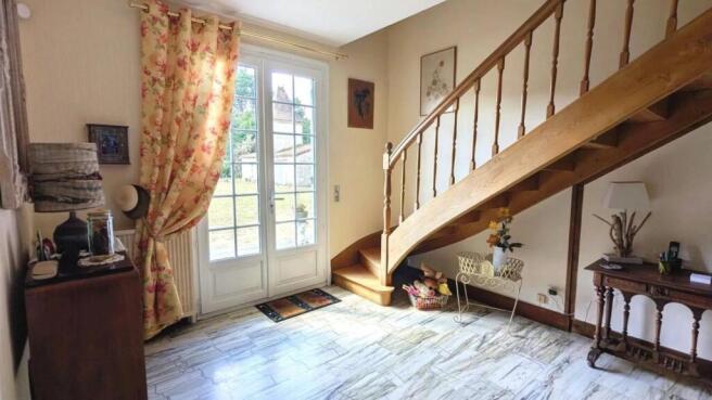 Une entrée lumineuse avec un escalier en bois et d
