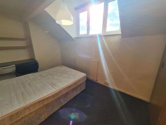 A cozy student bedroom featuring a single bed b...