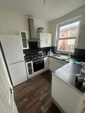 Bright galley-style kitchen with white cabinetr...