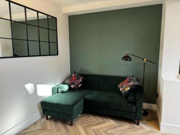 Stylish green velvet sofa and chic feature wall...