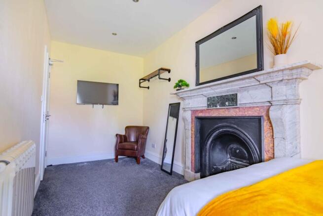 Double bedroom with marble fireplace and TV