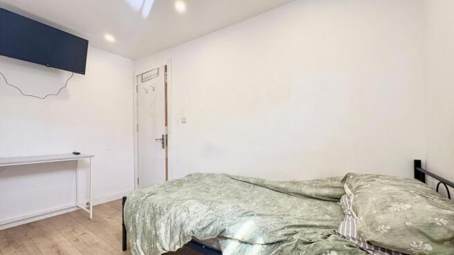 Bright bedroom with wall-mounted TV and desk....