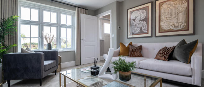 Bright living room with large window, white sofa, decorative cushions, coffee table, and wall art in
