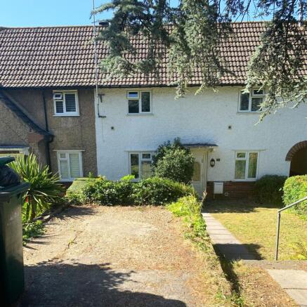 Sunny terraced house front with a pebbled drive...