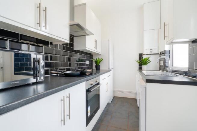 Modern kitchen with sleek white cabinetry, blac...
