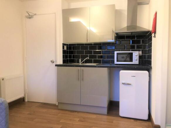 A modern and tidy compact kitchen featuring sle...