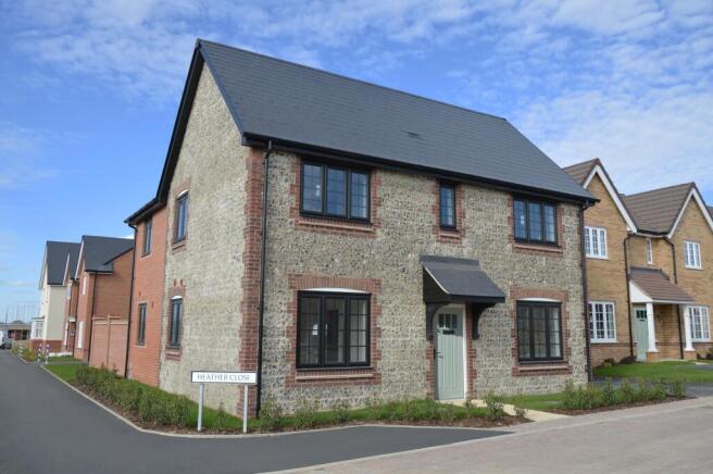 A modern stone-faced house with a dark roof stands on a paved street