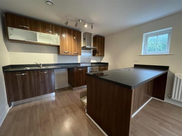 Modern kitchen with island and dark wood units...