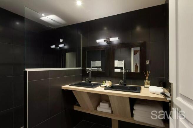 A modern bathroom with dark tiles features two sin