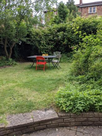 A well-maintained garden with a table and chair...