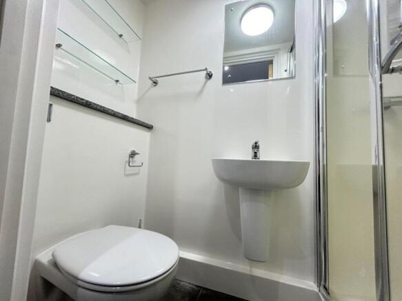 Clean modern ensuite with sleek glass shelving...