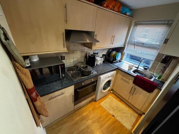 Compact fitted kitchen with light wood cabinets...