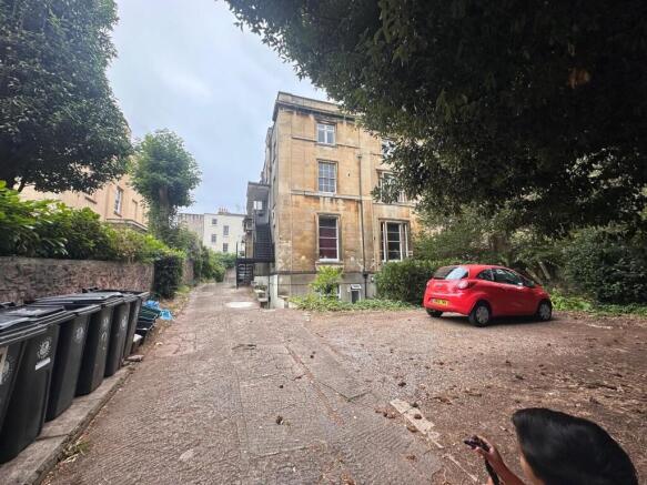 Stone-built period building set behind mature t...