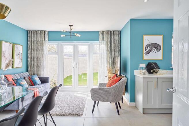 A modern living and dining area with a grey sofa and patterned armchair in the foreground