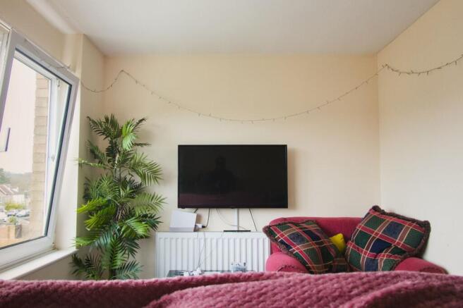 Bright bedroom with wall-mounted TV and greener...