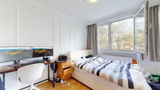 Bright bedroom with dual monitors and leafy vie...